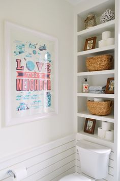 a white toilet sitting in a bathroom next to a shelf filled with pictures and candles