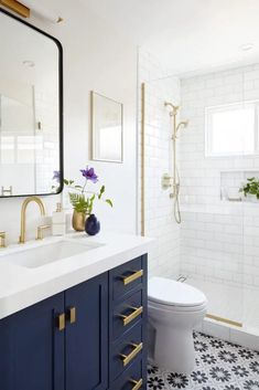 a white and blue bathroom with gold accents on the vanity, toilet and shower area