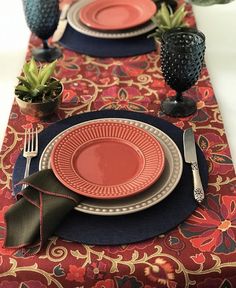 the table is set with red plates and black place mats, silverware, and succulents