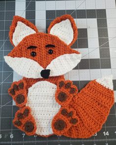 a crocheted fox sitting on top of a cutting board