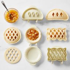 miniature pie molds are arranged on a marble counter top with spoons and saucers