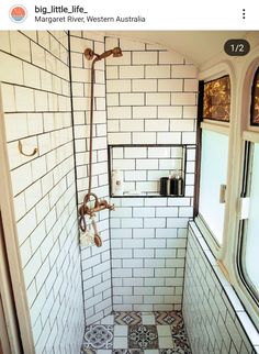 a bathroom with white and black tiles on the floor, shower head, and window