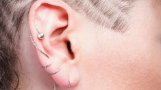 a person with ear piercings on their ears and behind the ear is a chain