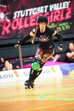 a woman rollerblading on an indoor court with people watching from the sidelines