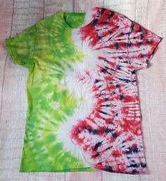 a green, red and white tie - dyed shirt laying on top of a wooden floor