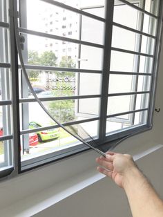 a person is holding scissors in front of a window