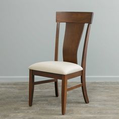 a wooden chair sitting on top of a hard wood floor next to a gray wall