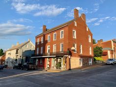 an old brick building on the corner of a street with cars parked in front of it