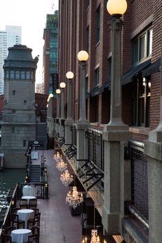 tables and chairs are lined up along the side of an alleyway with tall buildings in the background