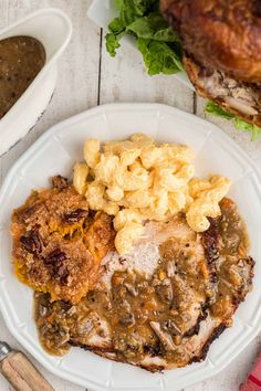 a white plate topped with meat covered in gravy and macaroni salad