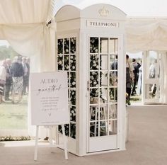 a white phone booth sitting in the middle of a field