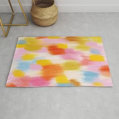 a multicolored area rug on the floor next to a basket and planter