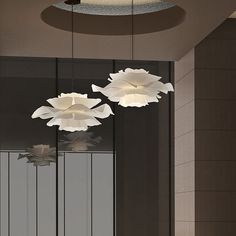 three white flowers hanging from the ceiling in a room with black walls and flooring