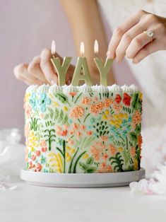 a woman is holding a birthday cake with candles that spell out the word yay