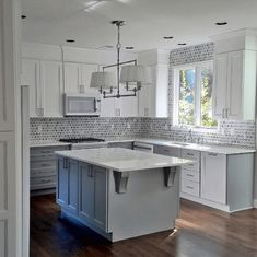 an empty kitchen with white cabinets and wood floors