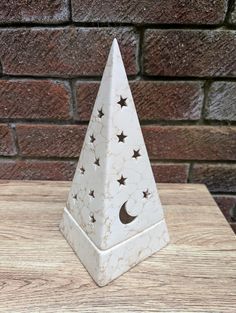 a white marble pyramid with stars and the moon on it sitting on a wooden table