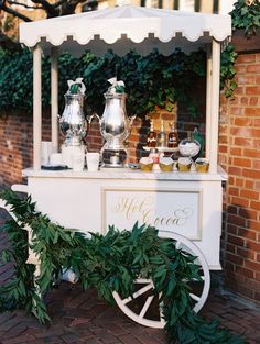 an old fashioned ice cream cart is decorated with greenery