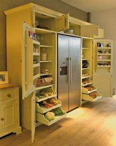 a kitchen with yellow cupboards and shelves filled with food