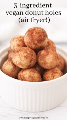 a white bowl filled with donuts covered in powdered sugar on top of a table