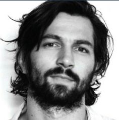 a black and white photo of a man with long hair, beard and wearing a shirt