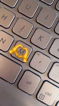 a yellow key sitting on top of a computer keyboard with the letter m in it