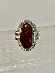 "Mexican Fire Agate set in Sterling Silver with a southwestern design work. The Fire Agate is a natural stone with a dark brown base color and bubbles of \"Fire\". This beautiful stone measures 19 mm by 10 mm. It is bezel set in Sterling Silver and has a rope design setting. The ring is measures 21mm long x 17mm wide. The band tapers to 4 mm Size- 7 Marked- none (tested and confirmed sterling Silver) Weight-4.58g" Brown Oval Agate Rings, Oval Brown Agate Rings, Brown Oval Rings With Natural Stones, Unique Brown Oval Rings, Oval Brown Rings With Natural Stones, Oval Brown Ring With Natural Stones, Artisan Brown Gemstone Rings, Brown Oval Cabochon Rings, Antique Amber Cabochon Rings