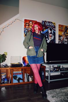 a woman with red hair is standing in front of a tv and some posters on the wall