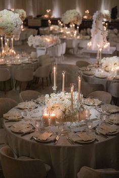 the tables are set with white flowers and candles