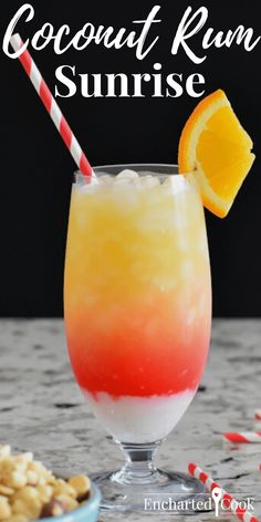 an orange and red drink in a glass next to cookies