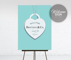 a welcome sign with a heart hanging from it's side on a easel