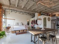 a room with a table, chairs and hanging clothes on the wall next to an oven