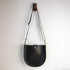 "With a classic saddle bag shape and convenient, magnetic snap closure, this is your new go-to bag. Easily fit everyday items including wallets, keys, phone, and more. We hand-cut buttery soft yet durable 5 oz Horween leather and stitch it with heavyweight nylon thread. The crossbody straps are available in multiple color options and are fitted with solid brass hardware. * Approximately 10\" x 10\" x 2\" * Crossbody strap drop adjusts from 16\" - 28\" * Magnetic snap closure * Unlined interior" Classic Saddle Bag With Adjustable Strap For On-the-go, Versatile Everyday Hobo Bag With Magnetic Closure, Everyday Shoulder Bag With Magnetic Closure, Classic Crossbody Saddle Bag For On-the-go, Everyday Saddle Satchel With Leather Handles, Versatile Everyday Bucket Bag With Magnetic Closure, Everyday Satchel Bag With Magnetic Closure, Versatile Everyday Satchel With Snap Closure, Classic Crossbody Bucket Bag For Everyday Use