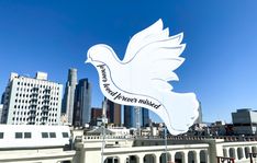 a large white sign with a dove on it in front of a cityscape