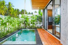 an indoor swimming pool surrounded by greenery next to a patio with sliding glass doors