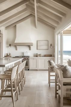 an open kitchen and dining room area with white cabinets, counter tops, and chairs