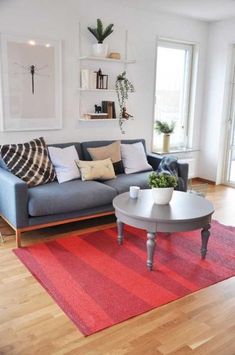 a living room filled with furniture and a red rug on top of a hard wood floor