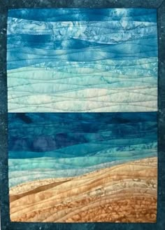 a quilted wall hanging on the side of a building with water and sand in it