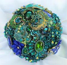 a close up of a brooch on a white cloth with blue and green beads