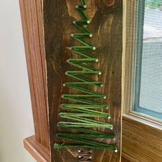 a christmas tree made out of string on top of a wooden shelf next to a window