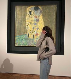 a woman standing in front of a painting talking on a cell phone