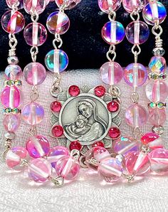 So ethereal, this beautiful fairytale pink rosary is made completely of smooth round mystic aura Quartz gemstones with aurora borealis Preciosa crystals, and they have a gorgeous blue rainbow that reflects in the light.  This gemstone has a very nice density, so this rosary is perfect if you like your rosary to have some weight to it. All of the prayers are said on the 8mm faceted gemstones, and the Pater prayers are flanked with embellishments and pink Preciosa crystal beads.  I have crystalliz Elegant Pink Rosary Bracelet For Wedding, Elegant Pink Wedding Rosary Bracelet, Pink Round Rosary Bracelet Gift, Pink 8mm Bead Jewelry For Valentine's Day, Pink Beaded Jewelry For First Communion, Pink 8mm Beads Jewelry For Wedding, Pink Spiritual Jewelry For First Communion, Pink Rosary, Mystic Quartz