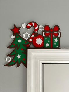 a decorated christmas tree next to a white framed frame with red and green decorations on it