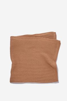 the rib knit headband in tan is folded up on a white surface and has a small