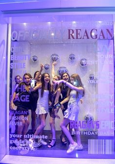 four girls posing in front of a window display