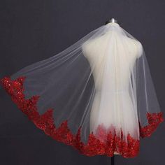 a white veil with red sequins on the bottom and sides is displayed in front of a mannequin's torso