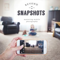 a person holding up a smart phone in front of a living room