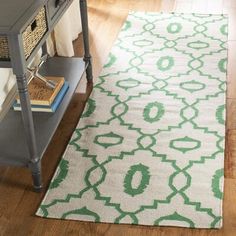 a green and white rug on the floor next to a table