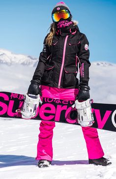 a woman standing in the snow with her snowboard and goggles on holding it