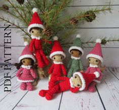 crocheted christmas gnomes are posed in front of a pine tree and pine cones