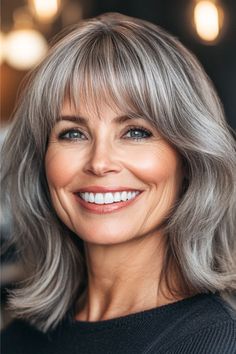 Medium-Length Silver Flipped Ends with Bangs Hairstyle on a smiling woman with gray hair. Natural Silver Hair, Flipped Ends, Long Hair Older Women, Beautiful Hairstyles